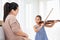 Girl playing violin with her pregnant mother for lullaby newborn in mother belly. Musical and entertainment concept