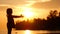 A girl plays ball on the seashore. Silhouette at sunset