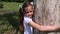 The girl plays in a green park. child hugs a large tree