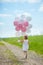 Girl plays in summer park with colorful baloons