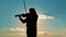 A girl plays the violin against the background of sunset, blue sky and sunlit clouds