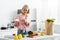 Girl pointing with finger at saucer with sweet cake near organic vegetables and fruits