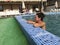 Girl in the pool outdoors. Leaned on board the pool. Smiling, sunglasses on his head