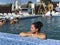 Girl in the pool outdoors. Leaned on board the pool. Smiling, sunglasses on his head