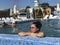 Girl in the pool outdoors. Leaned on board the pool. Smiling, sunglasses on his head