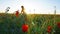 Girl on the poppy fields. Red flowers with green stems, huge fields. Bright sun rays.