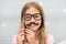 Girl pose with photo booth props glasses and mustache in bedroom. Child girl with party glasses. Child imitate