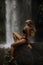 A girl poses in a bikini in a waterfall in a forest