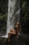 A girl poses in a bikini in a waterfall in a forest