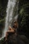 A girl poses in a bikini in a waterfall in a forest