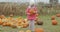 Girl posing with bright pumpkin in yard