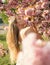 Girl posing next to blooming pink tree. Naked woman on flowery background, unity with nature concept. Perfect