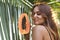 Girl posing in palm leaves on an island holding tropical fruit in hand