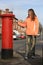 Girl posting letter to red british postbox