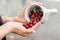 A girl pour on her hand from a mug berries of gooseberries_