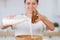 Girl pouring milk and pour flour into a wooden cup for making dough close up