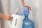 A girl pours water from a cooler in a teapot.