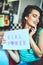 Girl power. an attractive young woman holding up a sign in a retro diner.