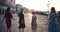 Girl power concept. Camera follows four young happy diverse women walk posing along summer sunrise Venice pier square.