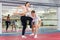 Girl practicing elbow and knee strikes with arm hold to male sparring partner at gym