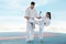 Girl practicing karate with coach on tatami outdoors