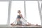 Girl practicing yoga, doing splits, stretching exercise on windowsill at home