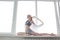 Girl practicing yoga, doing splits, stretching exercise on windowsill at home