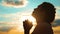Girl praying. girl folded her hands in prayer silhouette at sunset. slow lifestyle motion video. Girl folded her hands