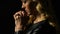 Girl praying isolated on black, light falling on face as sign of forgiveness