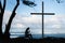 Girl praying to God in front of a cross with a beautiful blue ocean background.