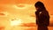 The girl prays. Girl folded her hands in prayer silhouette at sunset. slow motion video. Girl folded her hands in prayer