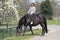 Girl on a pregnant brown horse without a saddle, with white blossom in the background