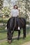 Girl on a pregnant brown horse without a saddle, with white blossom in the background