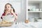 Girl preparing food in bowl, using wire whisk and licking finger