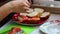 The girl is preparing sandwiches, puts the salmon on a loaf. Close-up on a white background.