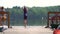 Girl preparing to swim in the lake from wooden pier. Having fun on summer day. Child wears a cold water swimsuit.