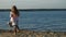 Girl preschool girl  playing with a brown labrador dog on the beach. Spring or cold summer