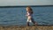 Girl preschool girl  playing with a brown labrador dog on the beach. Spring or cold summer