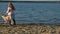 Girl preschool girl  playing with a brown labrador dog on the beach. Spring or cold summer