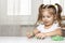 Girl preschooler sits at a table and sculpts from green dough for warm