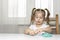 girl preschooler sits at a table and sculpts from turquoise dough for modeling