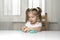 Girl preschooler sits at a table and sculpts from turquoise dough for modeling