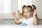 Girl preschooler sits at a table and sculpts from turquoise dough for modeling. activities with children at home on self-isolation