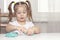 Girl preschooler sits at a table and sculpts from turquoise dough for sculpting