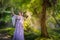 Girl in a princess dress is in a mysterious deep forest with trees, flowers and waterfalls