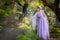 Girl in a princess dress is in a mysterious deep forest with trees, flowers and waterfalls