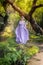 Girl in a princess dress is in a mysterious deep forest with trees, flowers and waterfalls