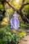 Girl in a princess dress is in a mysterious deep forest with trees, flowers and waterfalls