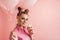 Girl with professional pink makeup and balloons enjoys delicious cupcakes. Portrait of woman with sweets on pink background