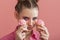 Girl with professional pink makeup enjoys delicious cupcakes. Portrait of woman holding pink cupcakes near her face on pink